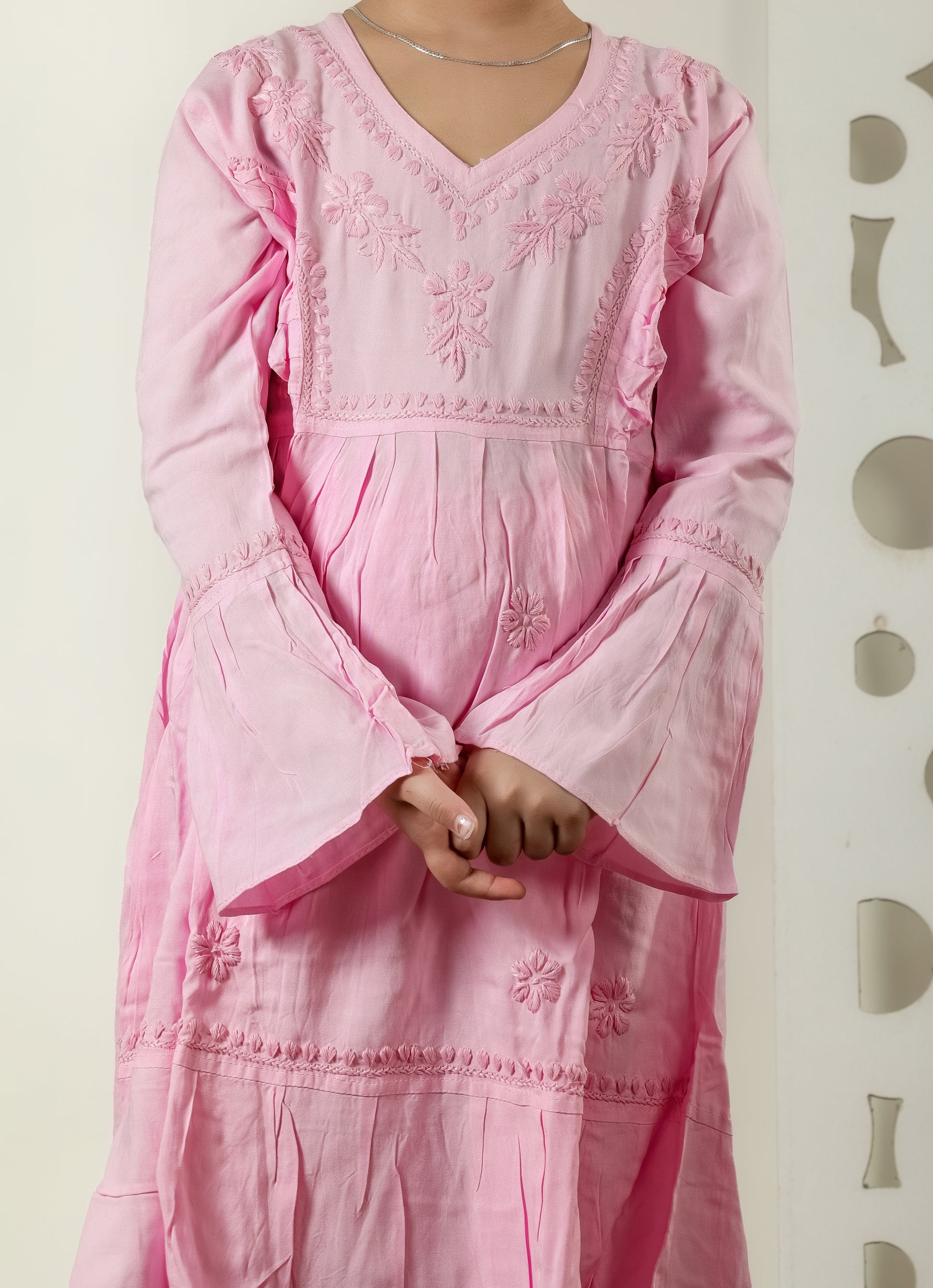 Person wearing a pink embroidered dress against a plain background