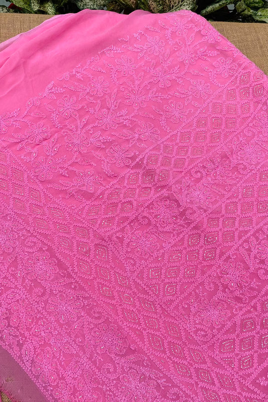 Pink embroidered fabric with intricate floral and geometric lace patterns, laid flat on a neutral surface.