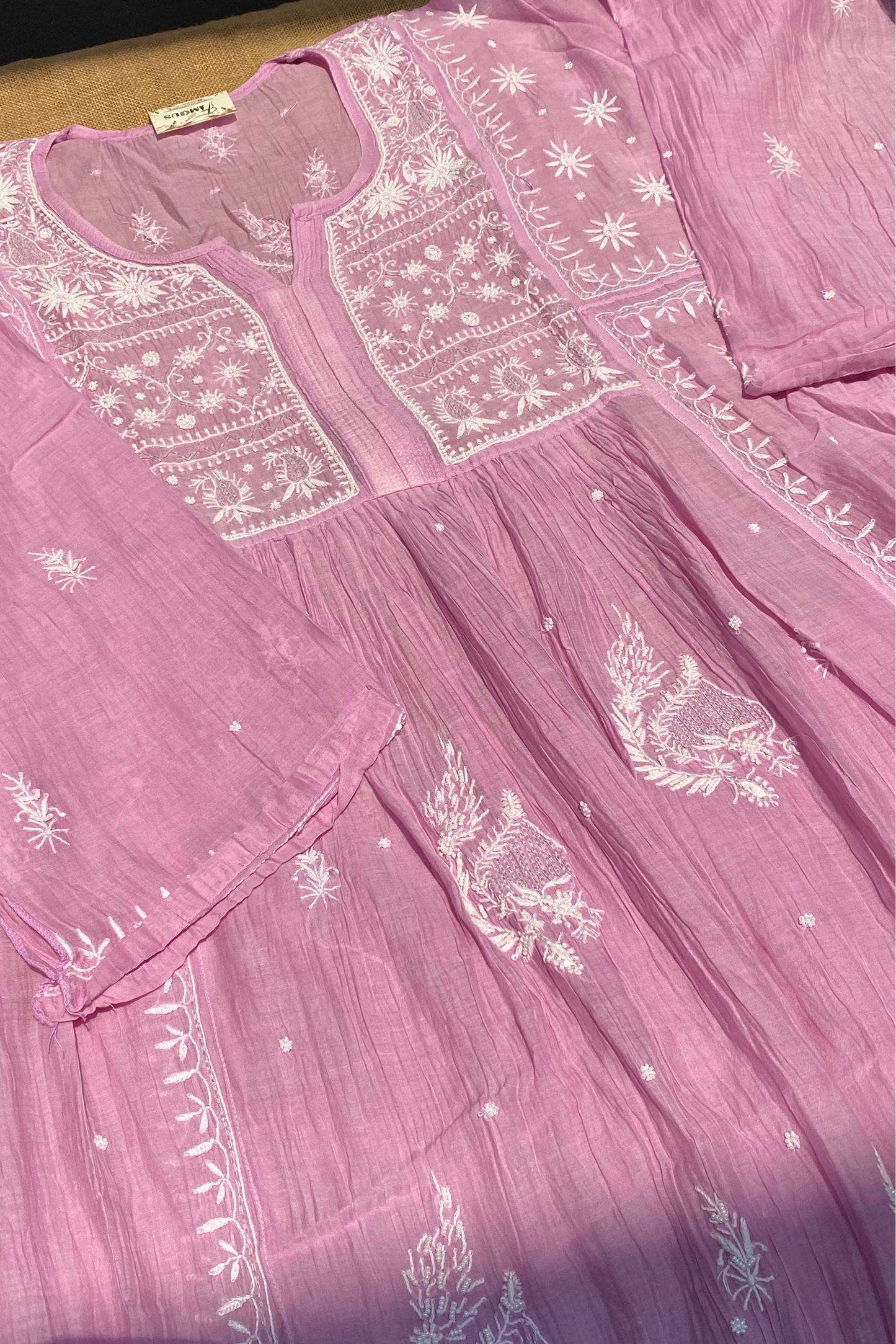 Pink dress with white embroidery on a wooden surface