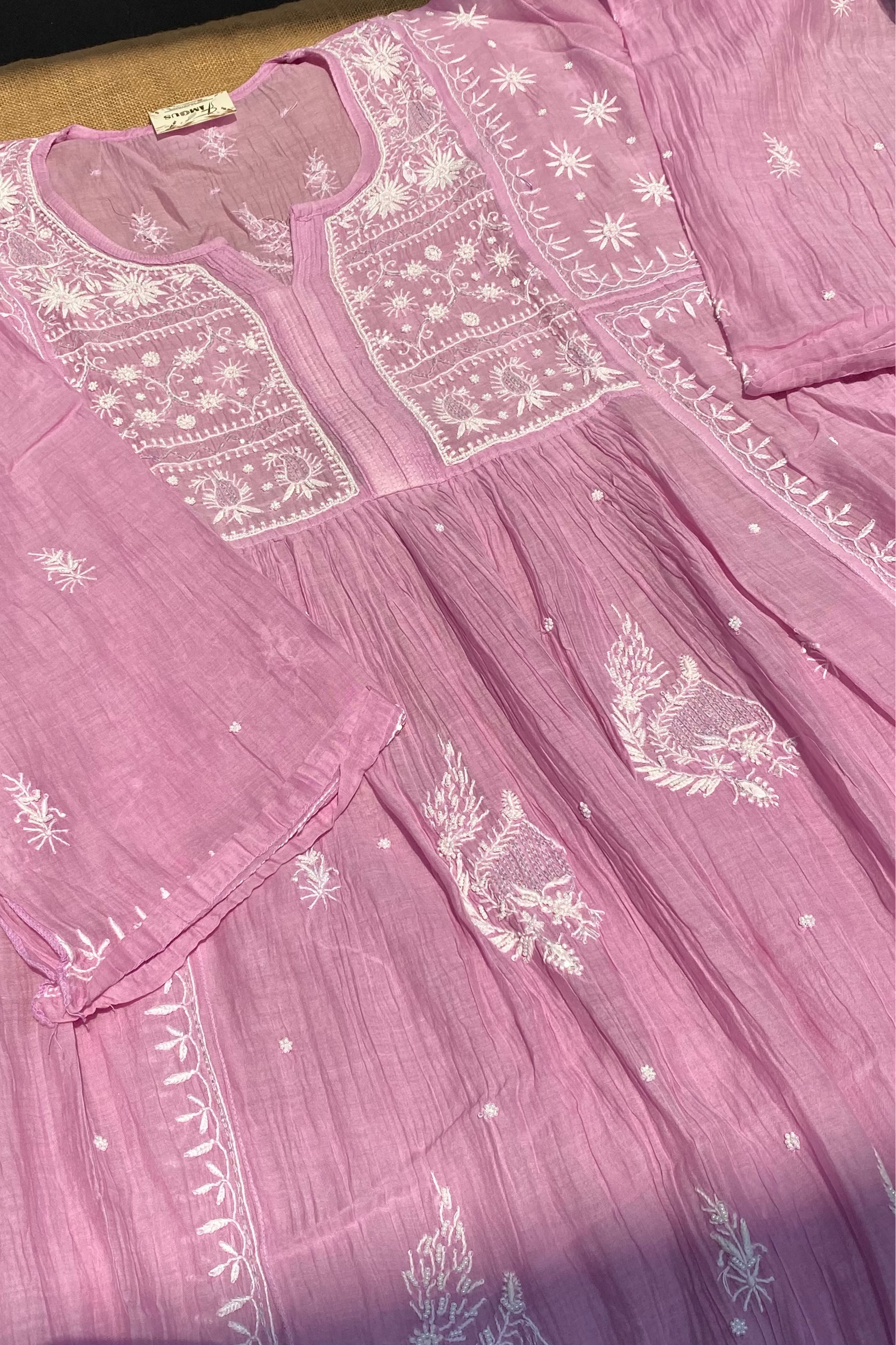 Pink dress with white embroidery on a wooden surface