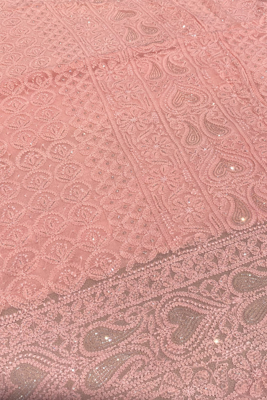 A close-up of dusty pink lace fabric with intricate floral and paisley embroidery, mesh backing, and scattered small silver glitter accents.
