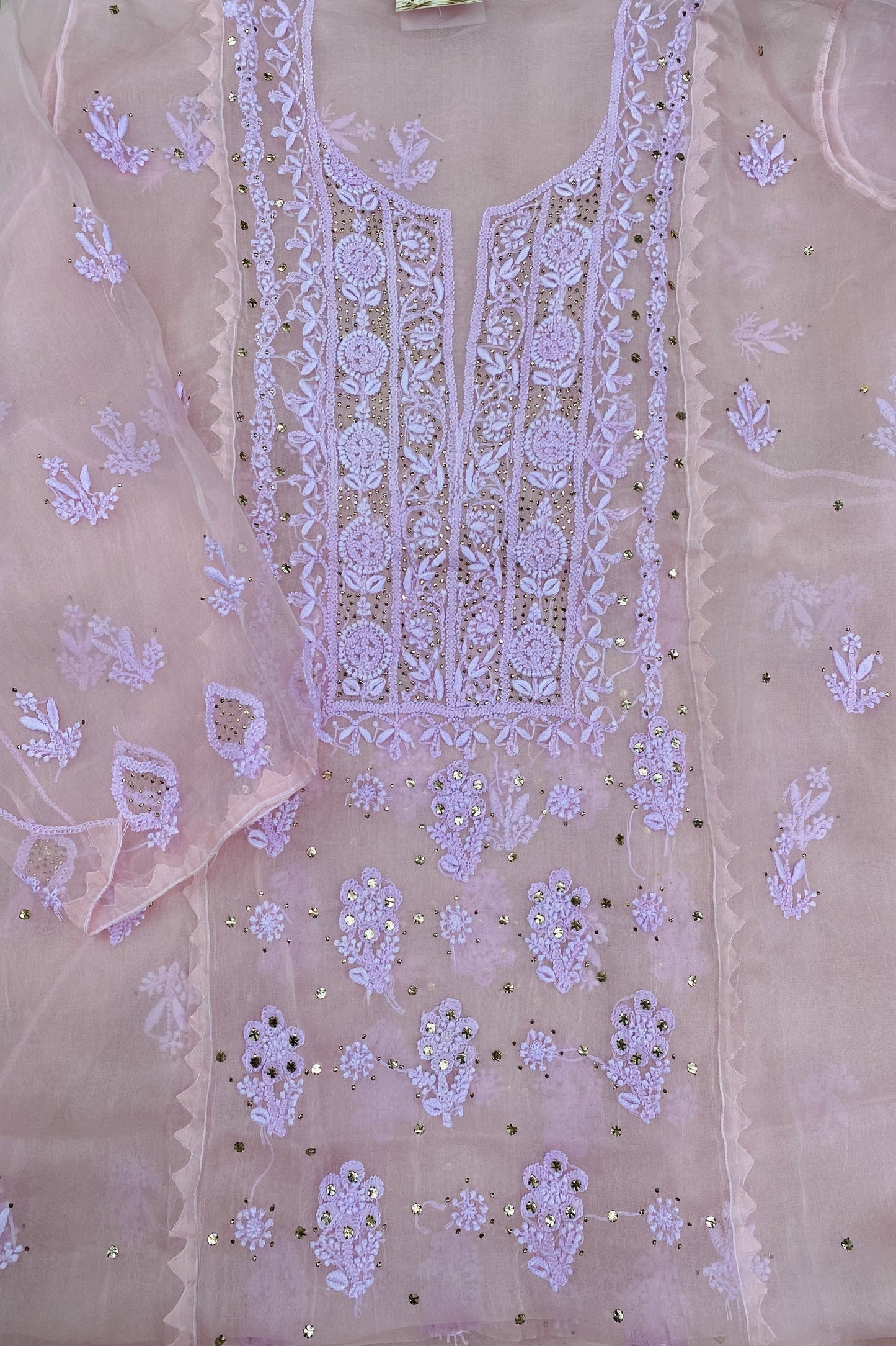 A light pink organza kurta with intricate lavender embroidery and sequin embellishments, laid flat.