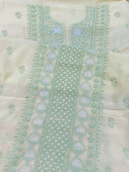 A close-up of a light beige or cream-colored embroidered fabric, likely part of an unstitched salwar suit set. The fabric features a prominent vertical panel with intricate mint green and light blue floral embroidery, geometric patterns, and small scattered motifs.
