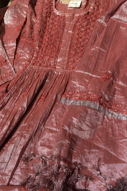 A close-up of a dusty rose pink traditional tunic or kurta with intricate red floral embroidery on the chest and a matching embroidered band on the skirt.