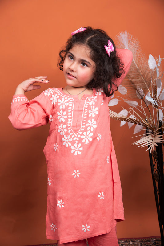 Young girl wearing a pink embroidered outfit against an orange background