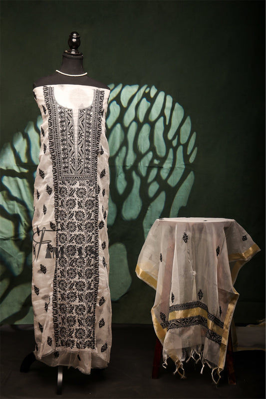 Mannequin wearing a white dress with black embroidery against a dark background