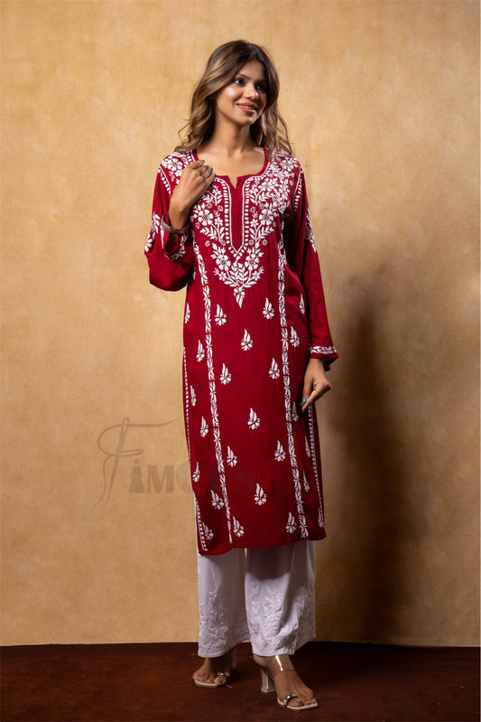 Woman wearing a red and white embroidered kurta with white pants against a brown background