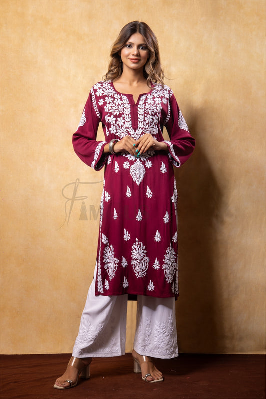 Woman wearing a maroon embroidered kurta with white pants against a beige background