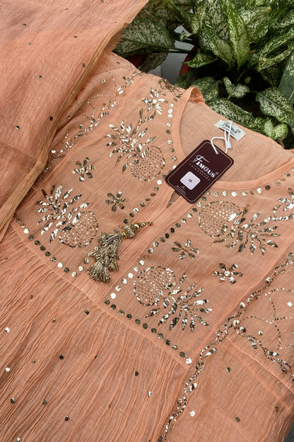 A peach-colored embroidered kurta with metallic silver and gold mirror work, featuring a matching sheer dupatta draped over the shoulder, with a brand tag visible.