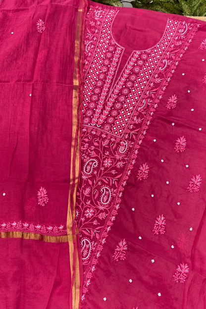 A magenta pink fabric set with detailed pink embroidery, featuring a solid panel, an embroidered yoke, and scattered small silver mirror work dots on a matching dupatta.