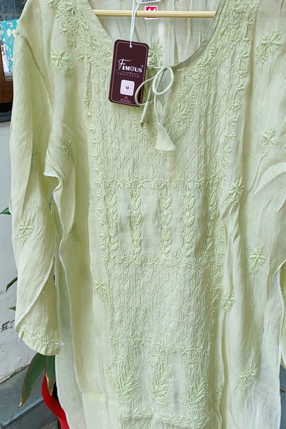 A pale yellow-green embroidered long-sleeve tunic top hanging on a wooden hanger with a visible brand tag reading 'Familiars'.
