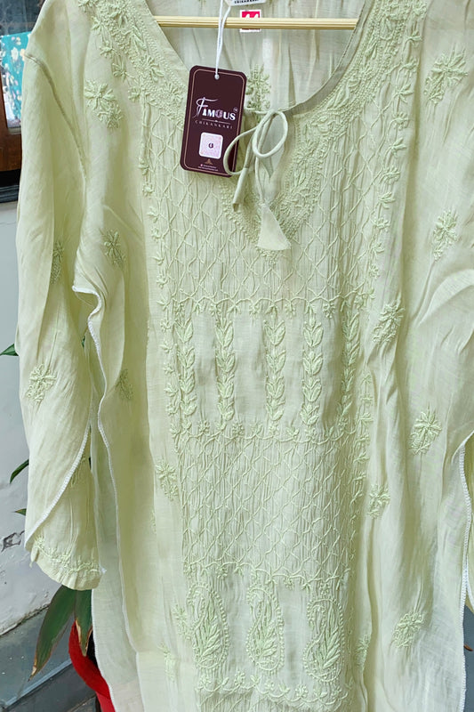 A pale yellow-green embroidered long-sleeve tunic top hanging on a wooden hanger with a visible brand tag reading 'Familiars'.