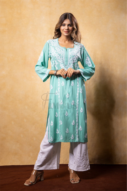 Woman wearing a teal embroidered kurta with white pants against a beige background
